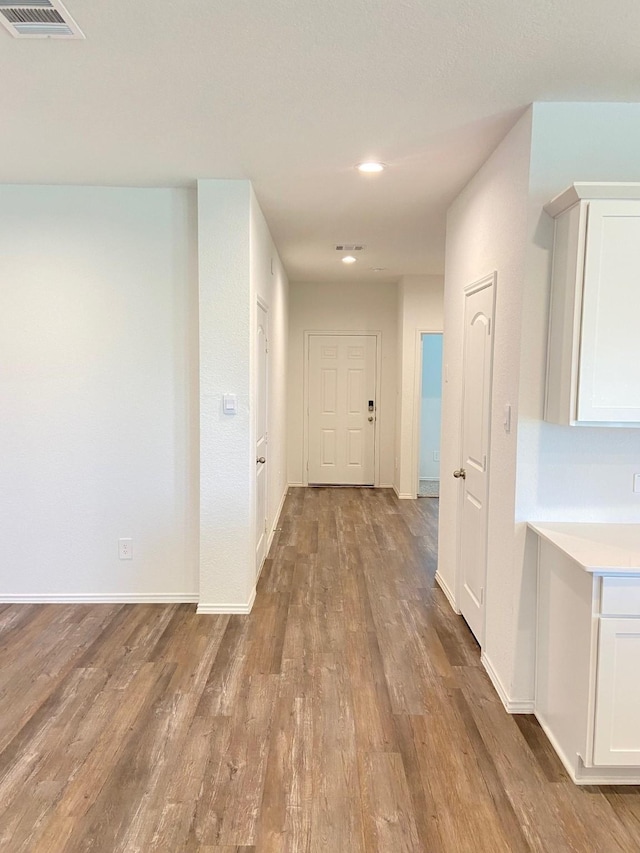 hall with baseboards, visible vents, wood finished floors, and recessed lighting