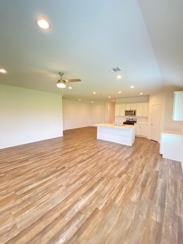 unfurnished living room featuring light wood finished floors, recessed lighting, a sink, and a ceiling fan