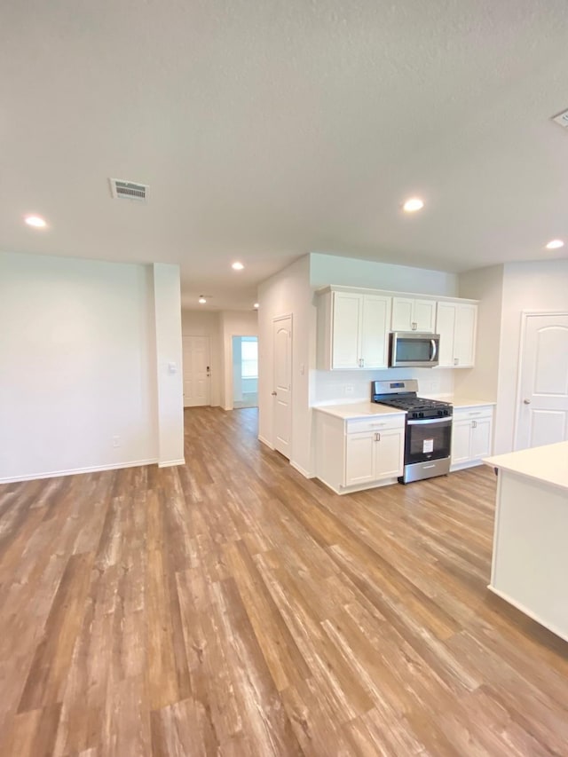 kitchen featuring visible vents, open floor plan, appliances with stainless steel finishes, and light wood finished floors