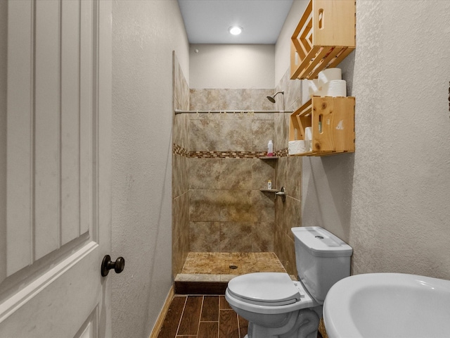 1151 County Line Rd, Shepherd, TX 77371 - bathroom with wood tiled floor, toilet, a textured wall, and tiled shower