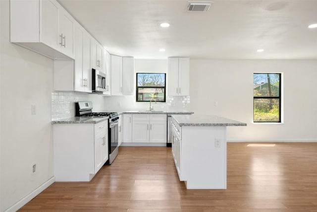 5610 Belarbor St, Houston, TX 77033 - kitchen featuring range with gas stovetop, plenty of natural light, stainless steel microwave, and visible vents