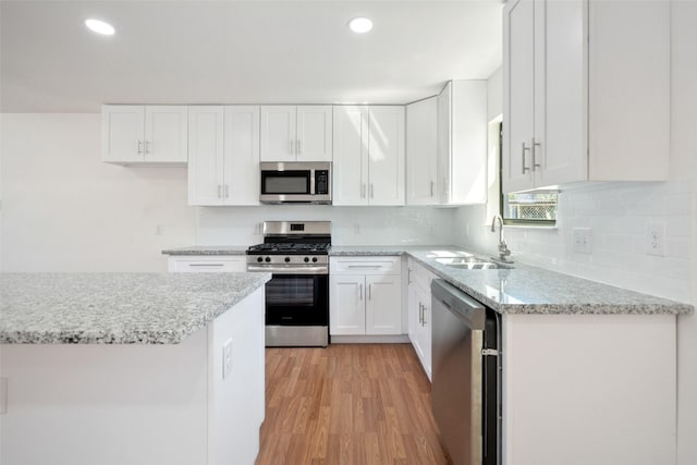 5610 Belarbor St, Houston, TX 77033 - kitchen with a sink, appliances with stainless steel finishes, light wood-style flooring, and white cabinets