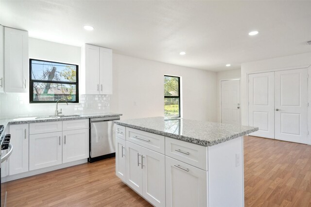 5610 Belarbor St, Houston, TX 77033 - kitchen with stainless steel dishwasher, light stone counters, light wood-style floors, and a kitchen island