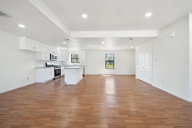 5610 Belarbor St, Houston, TX 77033 - kitchen featuring recessed lighting, light wood-style floors, appliances with stainless steel finishes, white cabinetry, and open floor plan