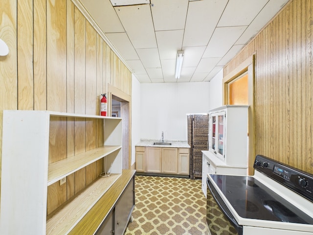 kitchen featuring light countertops, wooden walls, a sink, open shelves, and electric range