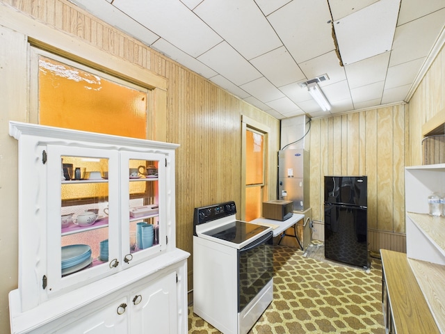 kitchen with light countertops, white range with electric stovetop, wooden walls, visible vents, and freestanding refrigerator