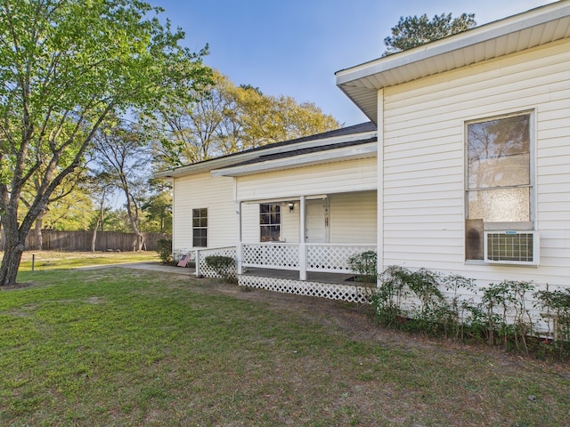 view of property exterior with covered porch, cooling unit, fence, and a yard