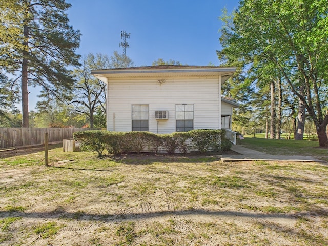 exterior space featuring a lawn, fence, and a wall unit AC