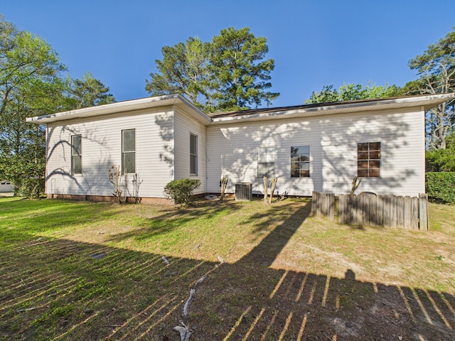 back of property with a lawn and central AC