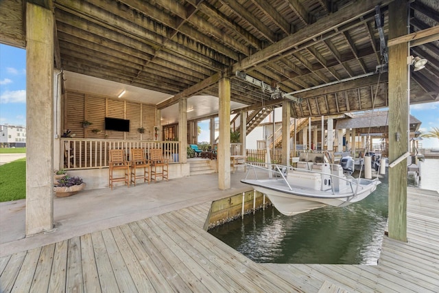 view of dock with a patio, a water view, and boat lift