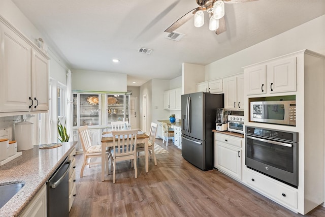 1518 Honea Egypt Rd, Magnolia, TX 77354 - kitchen featuring light stone countertops, visible vents, ceiling fan, appliances with stainless steel finishes, and wood finished floors