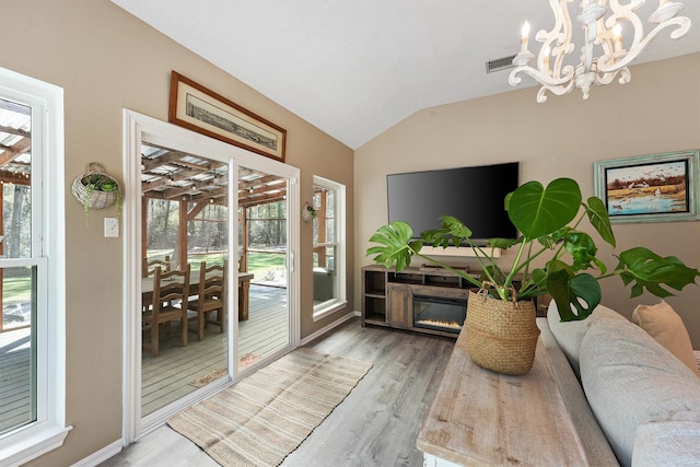 1518 Honea Egypt Rd, Magnolia, TX 77354 - living area featuring visible vents, a chandelier, wood finished floors, vaulted ceiling, and a glass covered fireplace