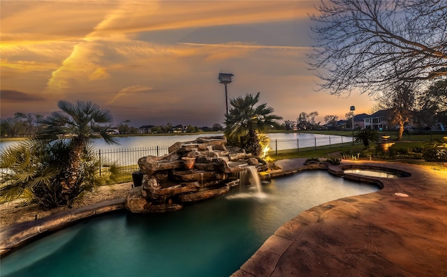 843 Royal Lakes Blvd, Richmond, TX 77469 - pool at dusk with a patio area, an in ground hot tub, a water view, and fence