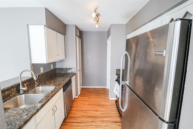 kitchen featuring baseboards, light wood-type flooring, white cabinets, a sink, and stainless steel appliances