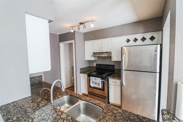kitchen featuring appliances with stainless steel finishes, a sink, dark stone countertops, under cabinet range hood, and white cabinetry