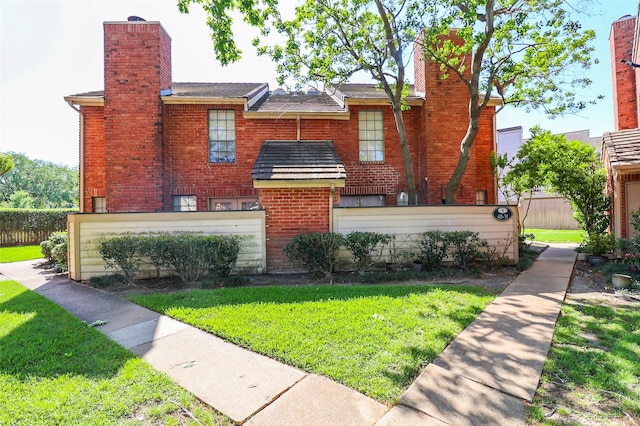 view of front of property with brick siding, a front lawn, and a chimney