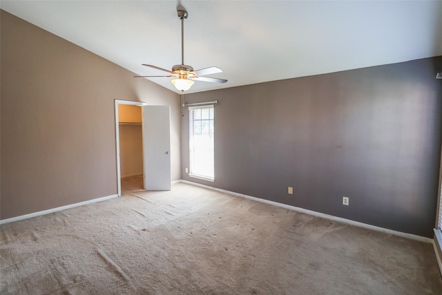 unfurnished bedroom featuring vaulted ceiling, baseboards, carpet flooring, and a walk in closet