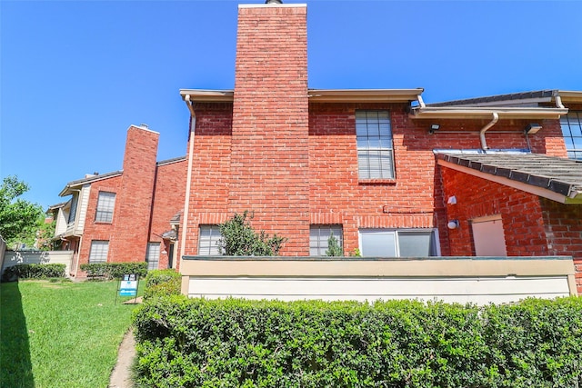 view of home's exterior featuring brick siding, a lawn, and a chimney