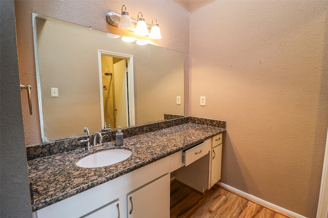 full bathroom with baseboards, a textured wall, wood finished floors, and vanity
