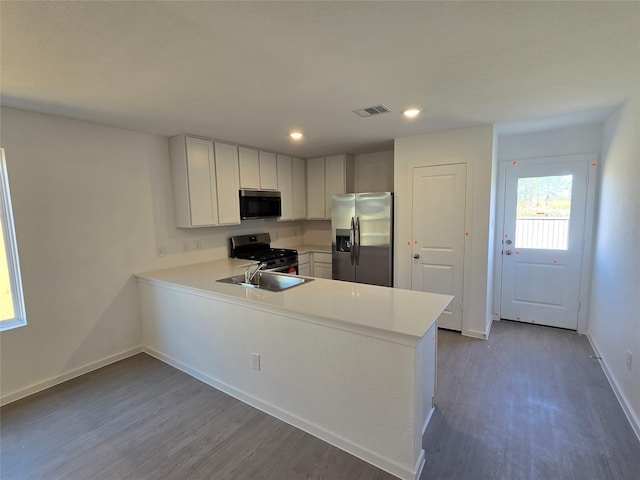 kitchen featuring visible vents, wood finished floors, light countertops, a peninsula, and stainless steel appliances