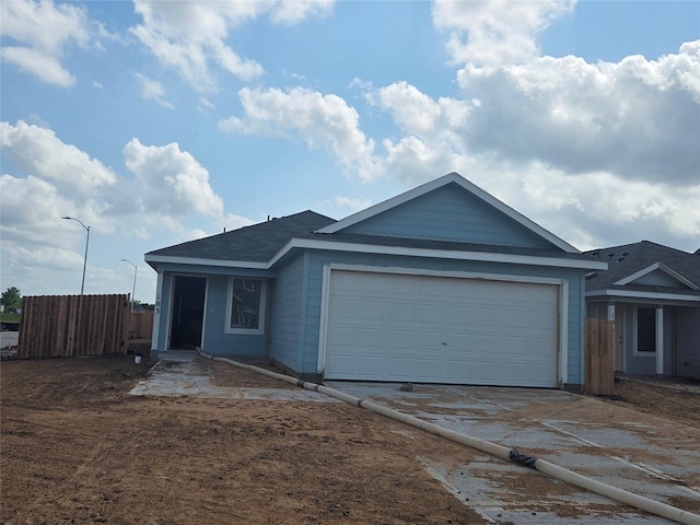ranch-style home featuring concrete driveway, fence, and a garage