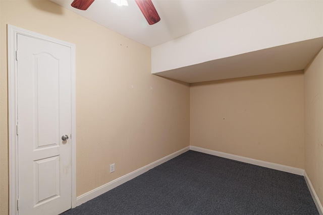 additional living space with baseboards, dark colored carpet, and ceiling fan