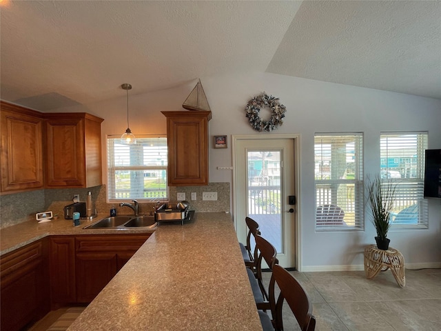 kitchen featuring a sink, lofted ceiling, and brown cabinets