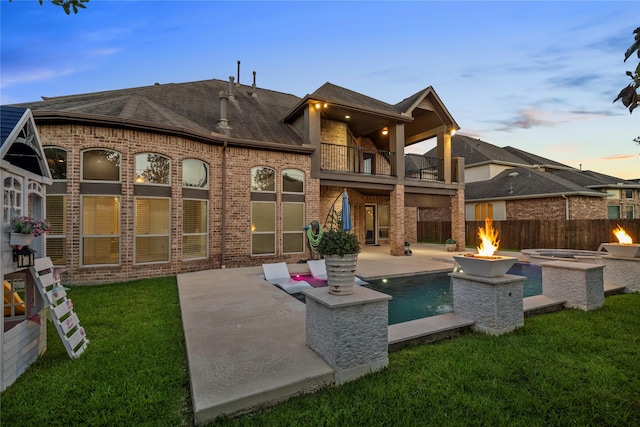 1038 Bolivar Point Ln, Friendswood, TX 77546 - back of property at dusk with a balcony, a fire pit, a patio, and brick siding