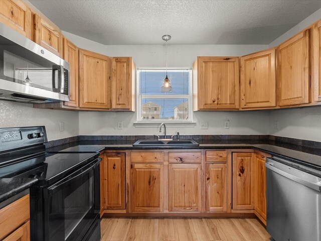 127 Howard, Surfside Beach, TX 77541 - kitchen with stainless steel appliances, a textured ceiling, a sink, dark countertops, and light wood-style floors