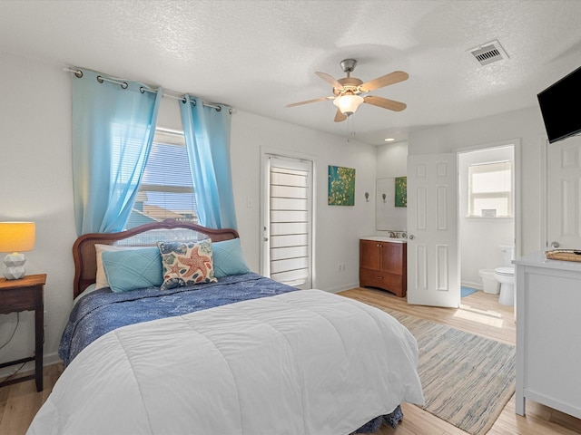 127 Howard, Surfside Beach, TX 77541 - bedroom with baseboards, a textured ceiling, connected bathroom, light wood finished floors, and visible vents