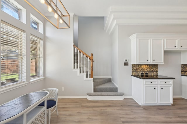 bar with tasteful backsplash, stairway, baseboards, light wood-type flooring, and hanging light fixtures