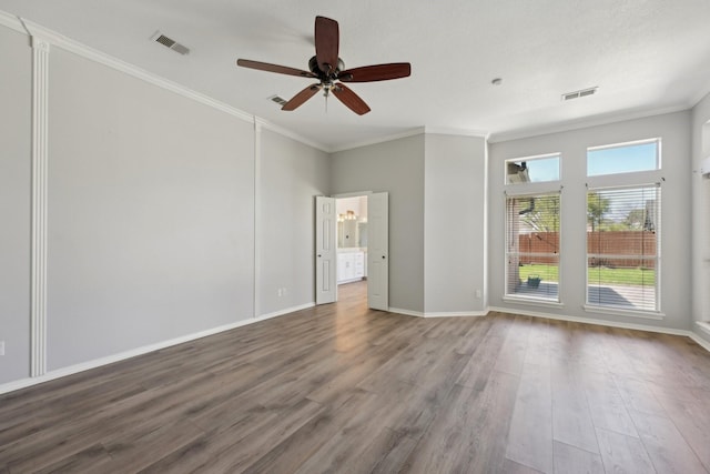 spare room featuring ornamental molding, visible vents, and wood finished floors