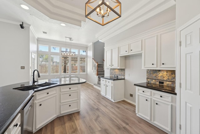 kitchen with a chandelier, stainless steel dishwasher, dark countertops, and a sink