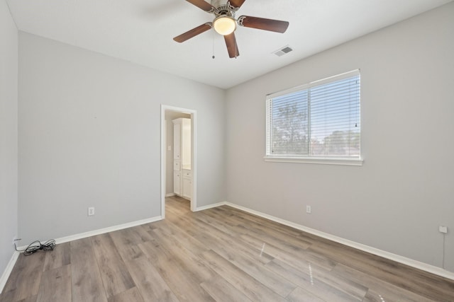 spare room with baseboards, visible vents, light wood-type flooring, and ceiling fan