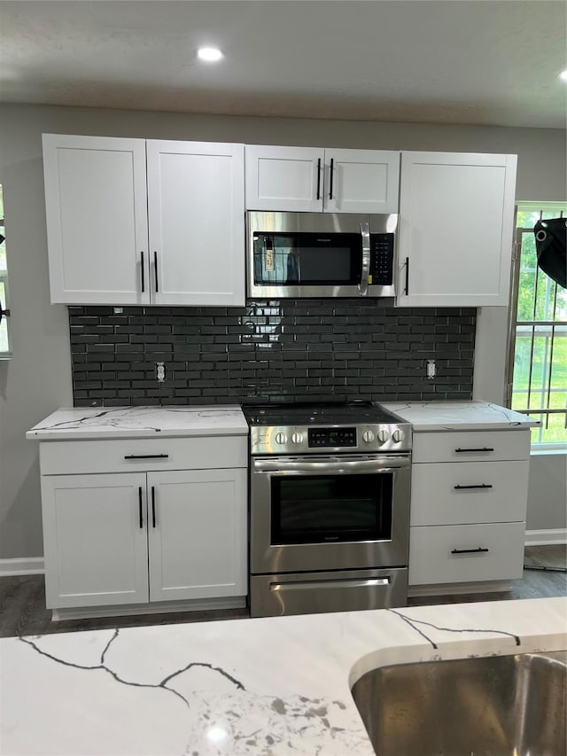 10525 Fairland Dr, Houston, TX 77051 - kitchen featuring light stone countertops, backsplash, appliances with stainless steel finishes, and white cabinets