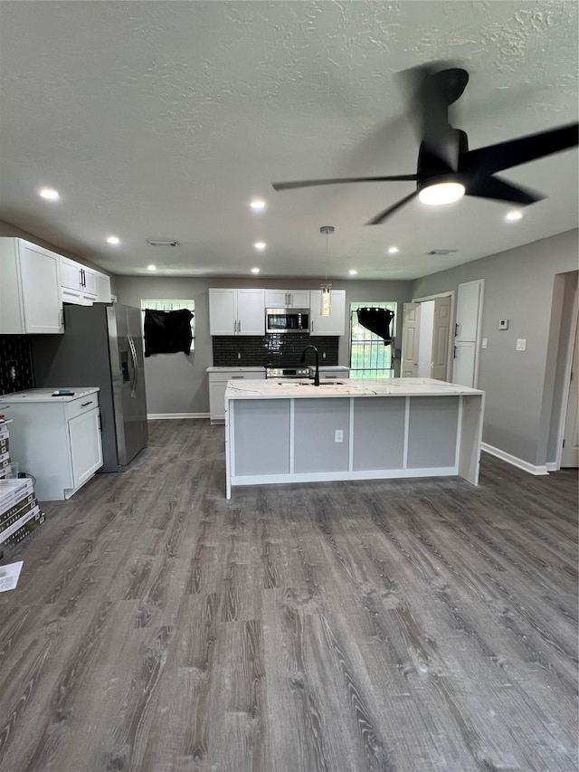 10525 Fairland Dr, Houston, TX 77051 - kitchen with dark wood-style floors, a ceiling fan, a center island with sink, and appliances with stainless steel finishes