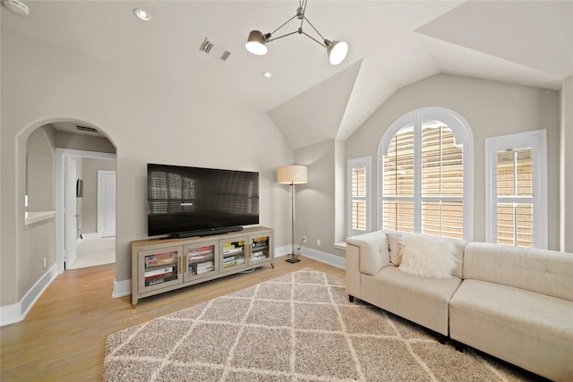 9219 Hummingbird Ln, Missouri City, TX 77459 - living room featuring wood finished floors, visible vents, baseboards, lofted ceiling, and arched walkways