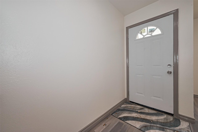 doorway featuring baseboards, vaulted ceiling, and wood finished floors