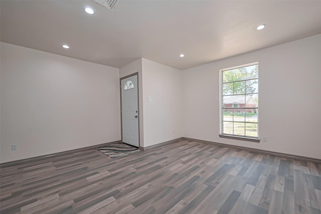 spare room with baseboards, wood finished floors, and recessed lighting
