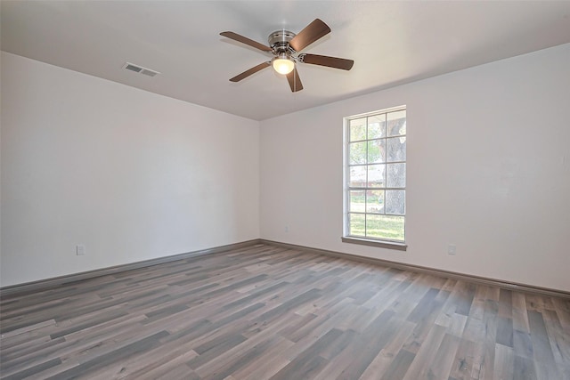 unfurnished room featuring baseboards, visible vents, a ceiling fan, and wood finished floors
