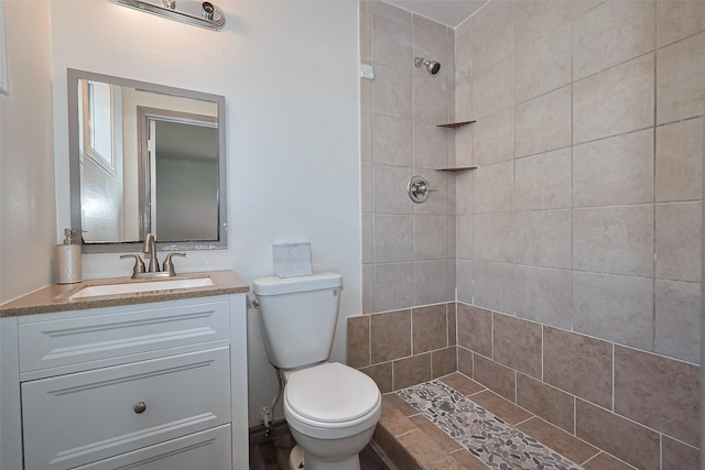 bathroom with toilet, vanity, and a tile shower