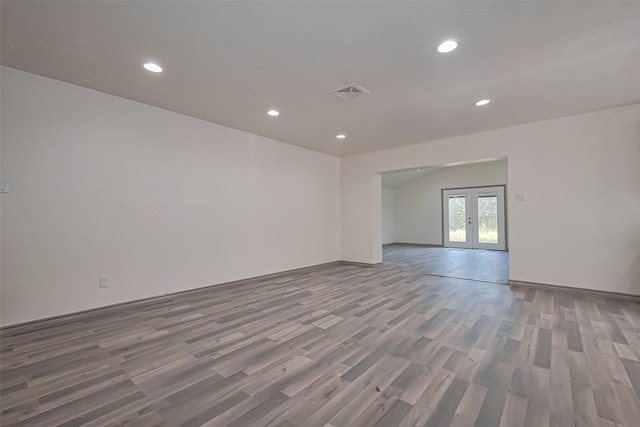 unfurnished room featuring french doors, visible vents, wood finished floors, recessed lighting, and vaulted ceiling
