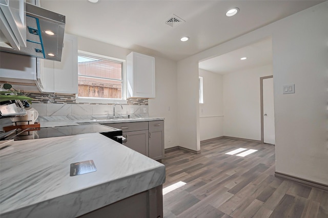 kitchen featuring light countertops, baseboards, decorative backsplash, visible vents, and wood finished floors