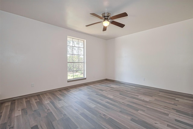 empty room featuring a ceiling fan, baseboards, and wood finished floors