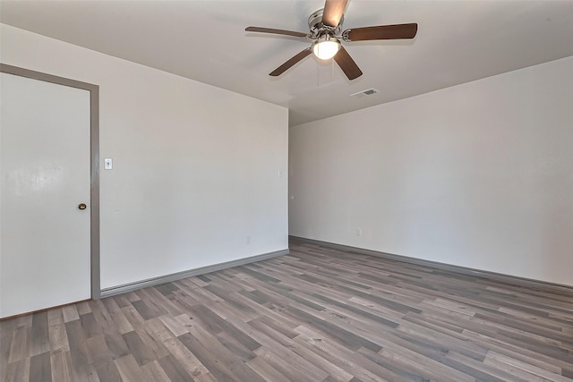 empty room featuring a ceiling fan, wood finished floors, and visible vents
