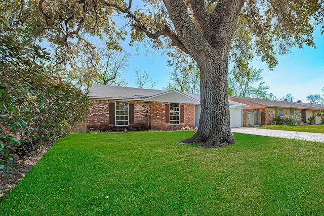 single story home featuring driveway, a front yard, an attached garage, and brick siding