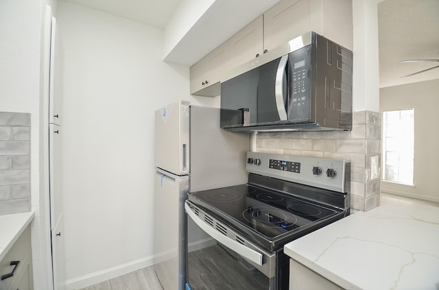 10501 S Dr Unit 300, Houston, TX 77099 - kitchen featuring light stone countertops, baseboards, decorative backsplash, appliances with stainless steel finishes, and light wood-type flooring