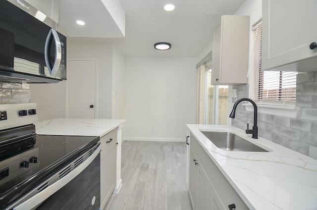 10501 S Dr Unit 300, Houston, TX 77099 - kitchen featuring light wood-style flooring, a sink, stainless steel appliances, decorative backsplash, and baseboards