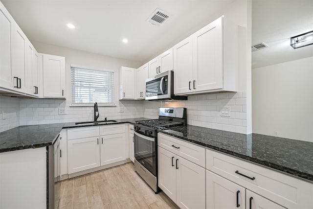 7119 Lumber Jack Dr, Houston, TX 77040 - kitchen featuring stainless steel appliances, a sink, dark stone countertops, light wood finished floors, and white cabinets