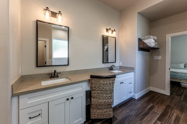 bathroom featuring connected bathroom, double vanity, baseboards, and a sink
